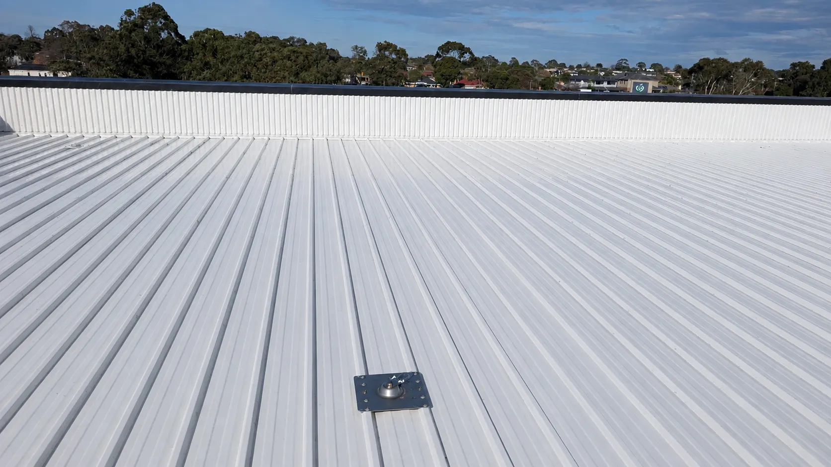 The same corrugated metal roof after cleaning, white channels and the same safety anchor