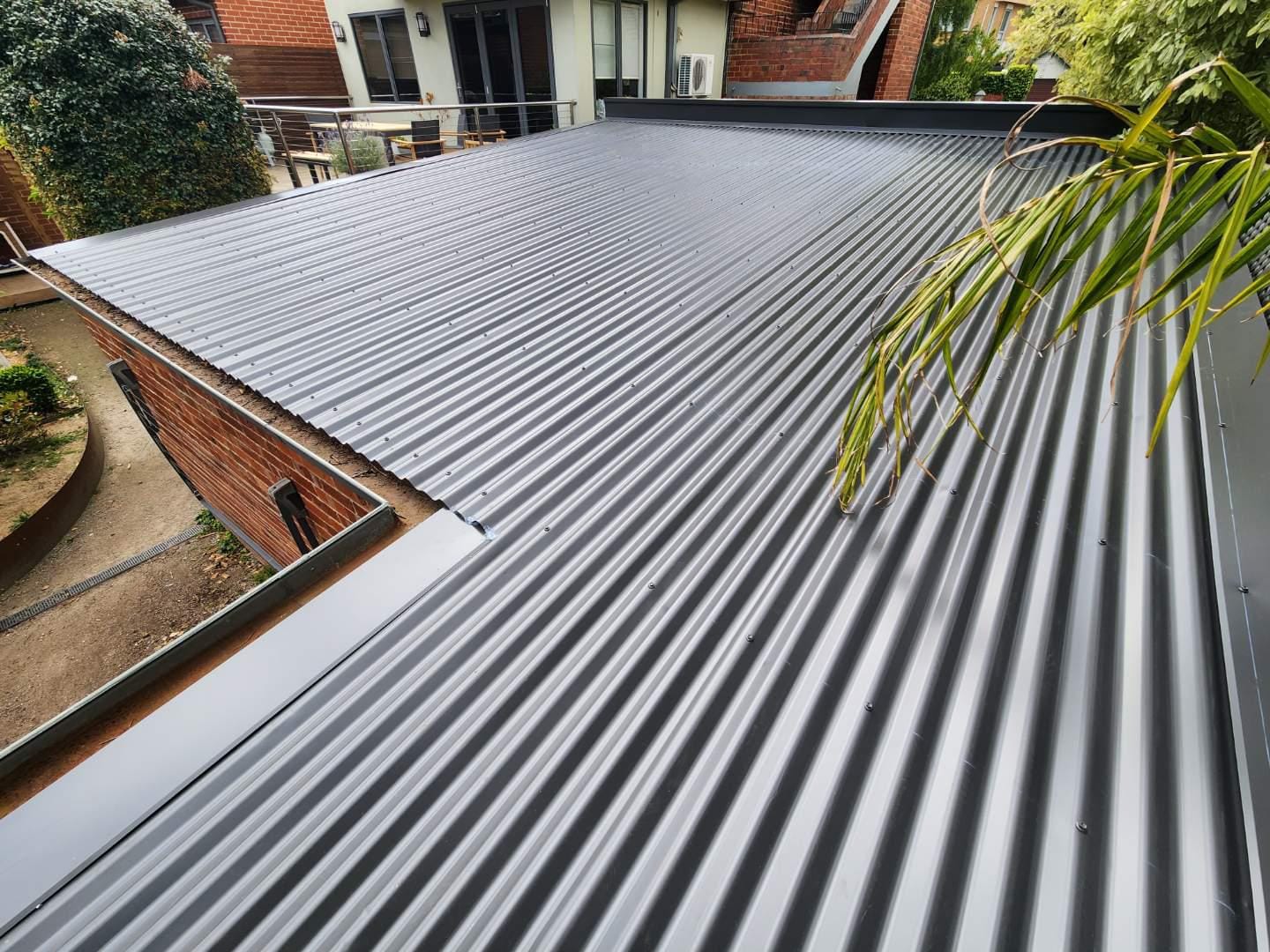 Dark corrugated low-pitch metal roof on a brick house