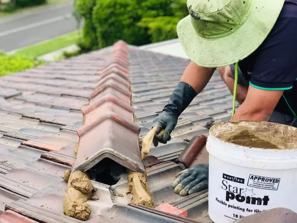 Hands working flexible pointing along a ridge, with a Westflex Starpoint bucket beside the work
