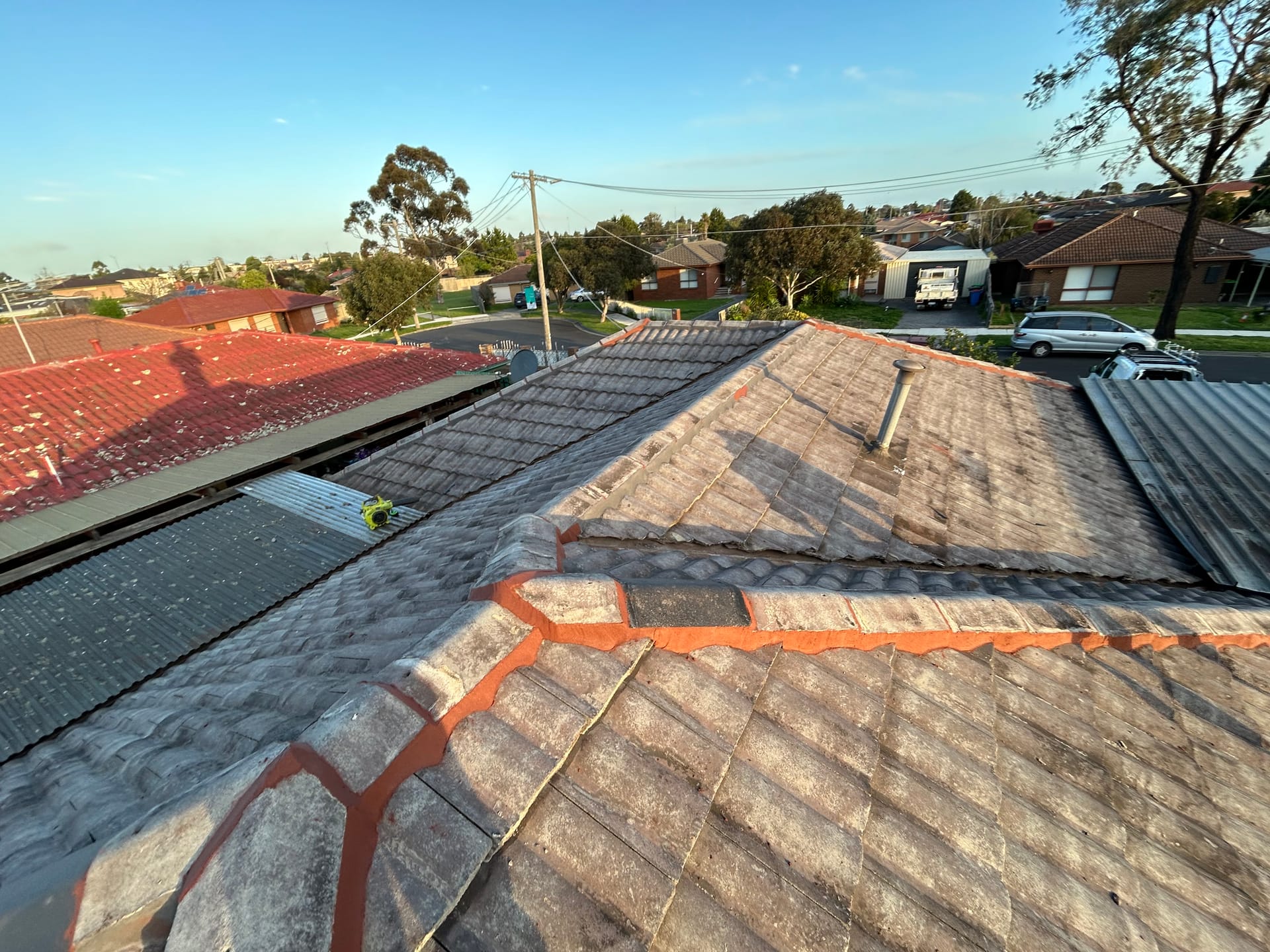 Weathered tiled roof with newly applied reddish pointing along the ridge