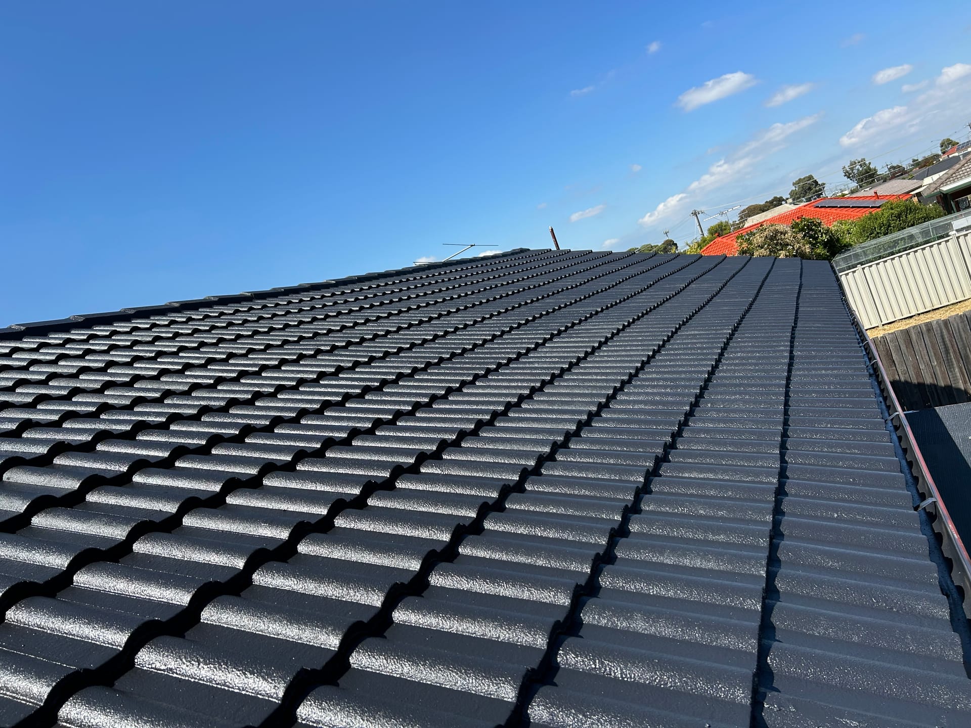 Glossy charcoal-coated tiled roof after colour restoration
