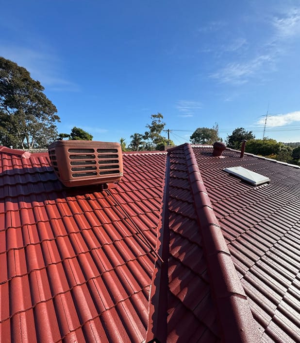 The same roof after a terracotta-red coating, ridge caps on, cooling unit still in place
