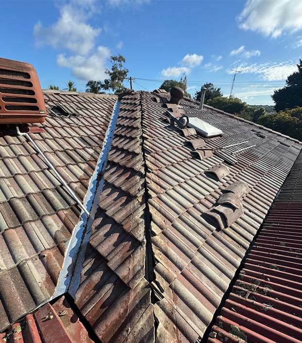 Weathered tiled roof with missing ridge caps, evaporative cooling and a skylight